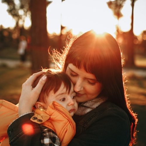 woman in black jacket carrying baby in red jacket