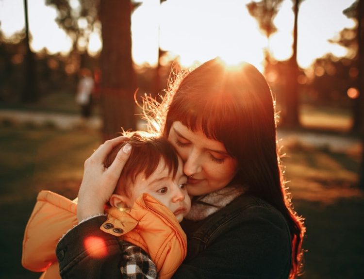 woman in black jacket carrying baby in red jacket