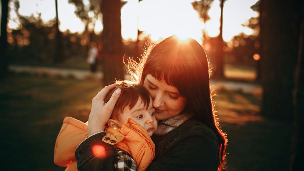 woman in black jacket carrying baby in red jacket